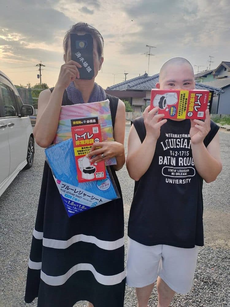 屋外で、簡易トイレとブルーシートを受け取られたお二人