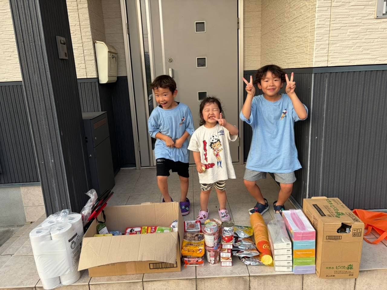 玄関前に並べた食料品や日用品と、お子さんたち